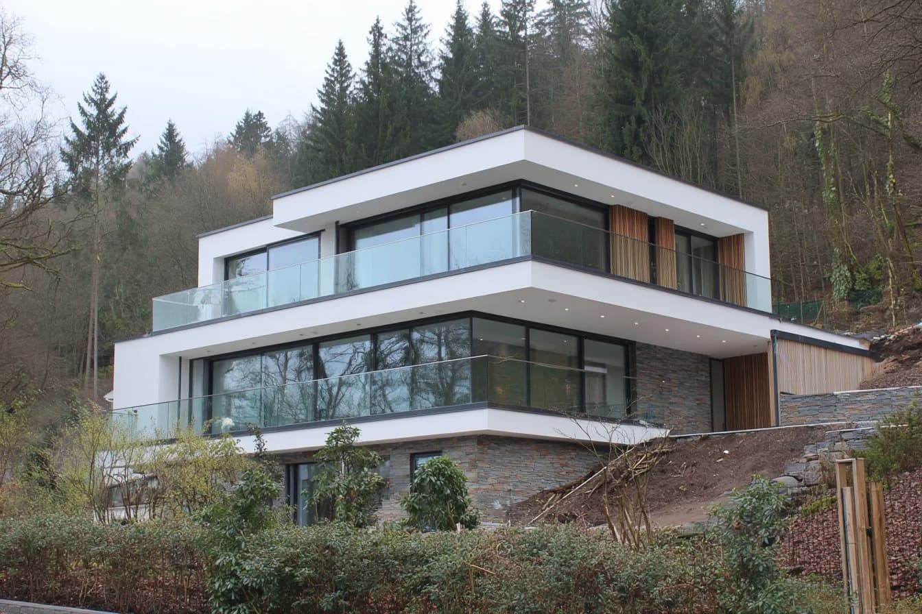 FS 1500 rahmenlose Glasbalustrade an Hanghaus mit Steinfassade und Wald