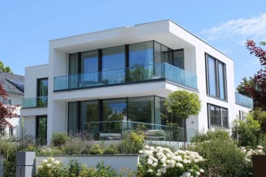 FS 1500 rahmenlose Glasbalustrade an Villa mit Garten und Blumen